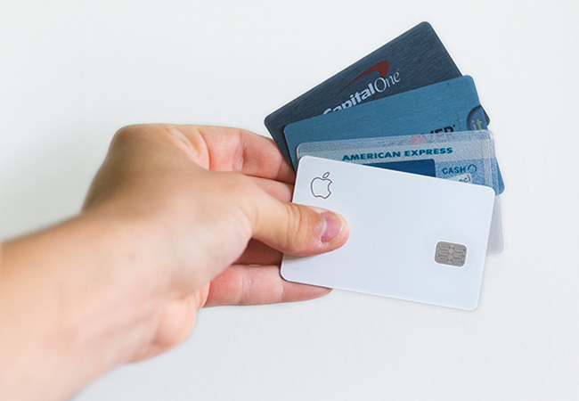 Zu sehen ist eine Hand, die vier Kreditkarten hält. Wenn Sie einem Online-Betrug auf den Leim gehen, können Sie eventuell das Geld zurückholen. Bild: Unsplash/Avery Evans